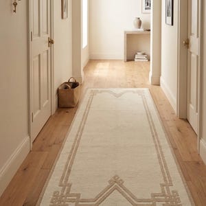 Elegante alfombra blanca con borde geométrico - Sofisticado detalle de greca griega en tonos neutros - Minimalista, rectangular, de lana beige - Elegante