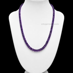 May include: A beaded necklace with small, faceted purple beads. The necklace is displayed on a white bust against a black background. The text "vickygemsa beads" is visible on the bust.