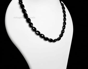 May include: A black beaded necklace displayed on a white bust against a black backdrop. The necklace features oval-shaped beads strung together. The brand name "vickygem beads" is visible on the bust.