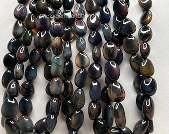 May include: Strands of polished, oval-shaped beads in shades of black, brown, and iridescent colors. The beads have a smooth, glossy finish and are strung together, creating a textured and visually appealing display. The beads are approximately 1 cm in length.
