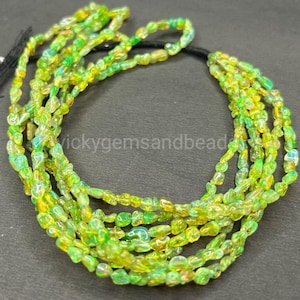 Puede incluir: Un collar de cuentas vibrantes de varios hilos. Las cuentas son una mezcla de amarillo y verde, con una calidad translúcida. El collar está ensartado en un cordón negro. El texto "vickygemsandbeads" es visible.