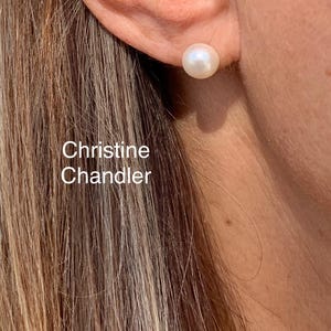 Puede incluir: Primer plano de la oreja de una mujer con un solo pendiente de perla blanca. El pendiente es de estilo sencillo.