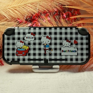 Op de afbeelding: Een zwart-wit geblokte gaming console hoes met Hello Kitty afbeeldingen. Het ontwerp toont Hello Kitty in een rode auto, op een springstok en met een bordje met de tekst Best Friends en het woord HELLO in een tekstballon.