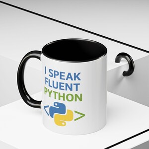 May include: White ceramic mug with a black interior and handle. The mug features the text "I SPEAK FLUENT PYTHON" in blue and green, along with a Python logo. A perfect gift for programmers.