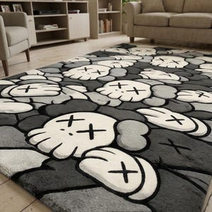 May include: A rectangular area rug featuring a repeating pattern of stylized white skulls with black X-shaped eyes and rounded gloved hands on a dark gray and light gray background. The rug has a soft, plush texture and covers a portion of the floor.