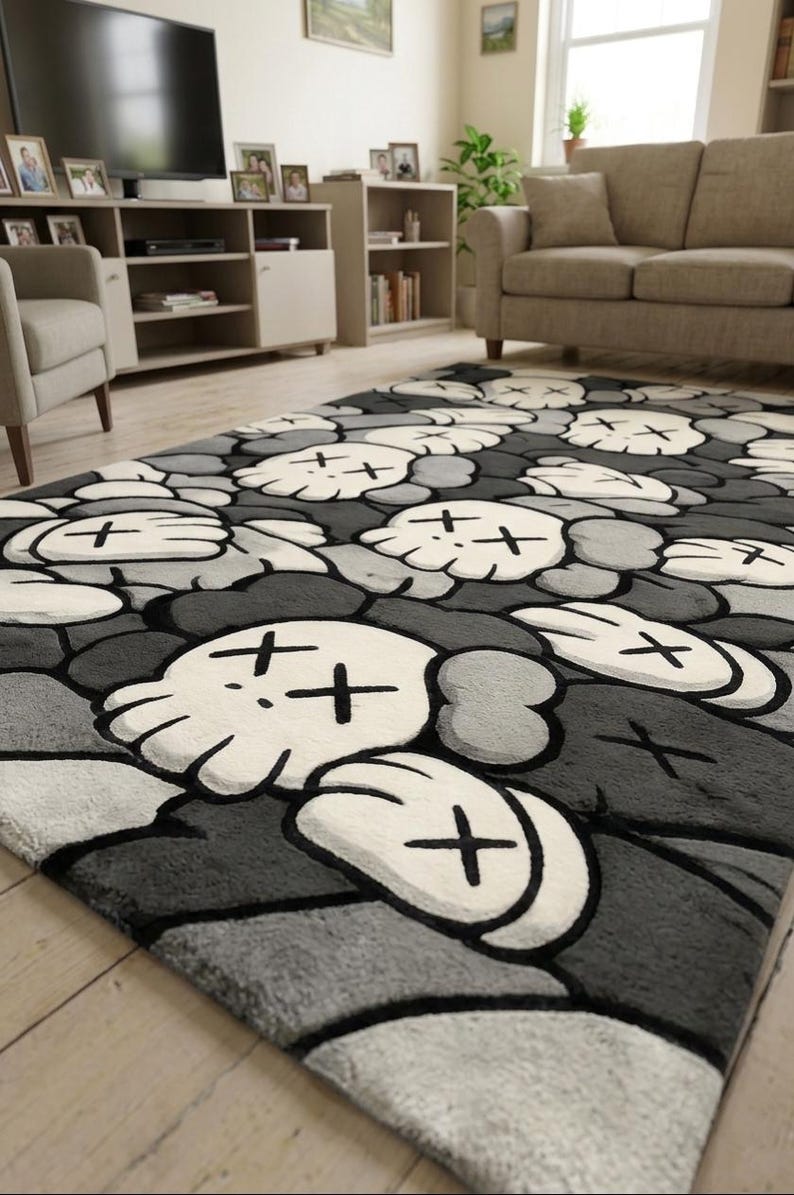 May include: A rectangular area rug featuring a repeating pattern of stylized white skulls with black X-shaped eyes and rounded gloved hands on a dark gray and light gray background. The rug has a soft, plush texture and covers a portion of the floor.
