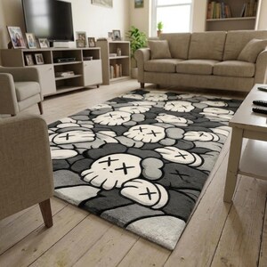 May include: A rectangular area rug featuring a repeating pattern of stylized skull-like figures with cross-shaped eyes. The design uses a monochromatic color palette of black, dark gray, light gray, and white, creating a dense, layered graphic effect.