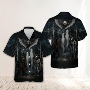May include: A short-sleeve button-down shirt in black featuring a dark forest graphic print. The design includes a large bat with a skull head, two tall ghostly figures, a hairy ape-like creature, and a skeletal deer-like figure in the woods.