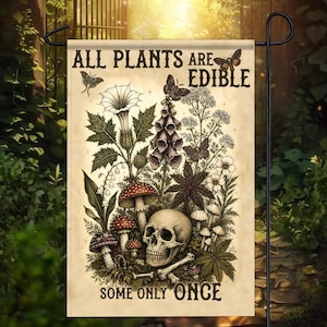 Könnte beinhalten: Eine rechteckige Gartenflagge mit einer botanischen Illustration im Vintage-Stil, die verschiedene Pflanzen, Pilze und einen menschlichen Schädel zeigt. Der Text lautet oben ALL PLANTS ARE EDIBLE und unten SOME ONLY ONCE, ergänzt durch Schmetterlinge.