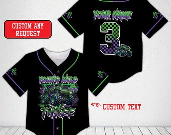 May include: Black baseball jersey with green and purple accents. The front features a monster truck graphic and the words "YOUNG WILD & THREE". The back has the number 3 and the text "YOUR NAME".