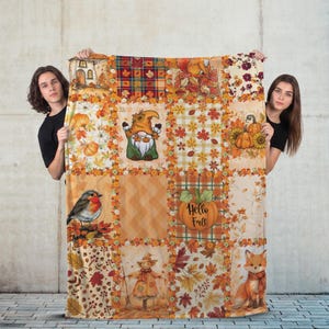 May include: A rectangular throw blanket featuring a patchwork design with autumn themes including a gnome, a robin, a fox, pumpkins, and fall foliage. The blanket displays various patterns such as plaid, chevron, and leaf prints in orange, yellow, and brown tones. The text Hello Fall is printed on a pumpkin graphic.