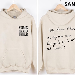 May include: Sand-colored hoodie with the text "YUNG BLUD IDOLS" on the front. The back of the hoodie features handwritten text that reads "Hello. Heaven Hello. One Stop into heaven First you'll go to hell and back...!"