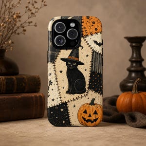 Könnte beinhalten: Eine Smartphone-Hülle mit Patchwork-Design, das eine schwarze Katze mit Hexenhut, einen Kürbis, Sterne und Fledermäuse zeigt. Der Hintergrund besteht aus cremefarbenen, schwarzen und orangefarbenen stoffartigen Mustern mit sichtbaren Nähten.