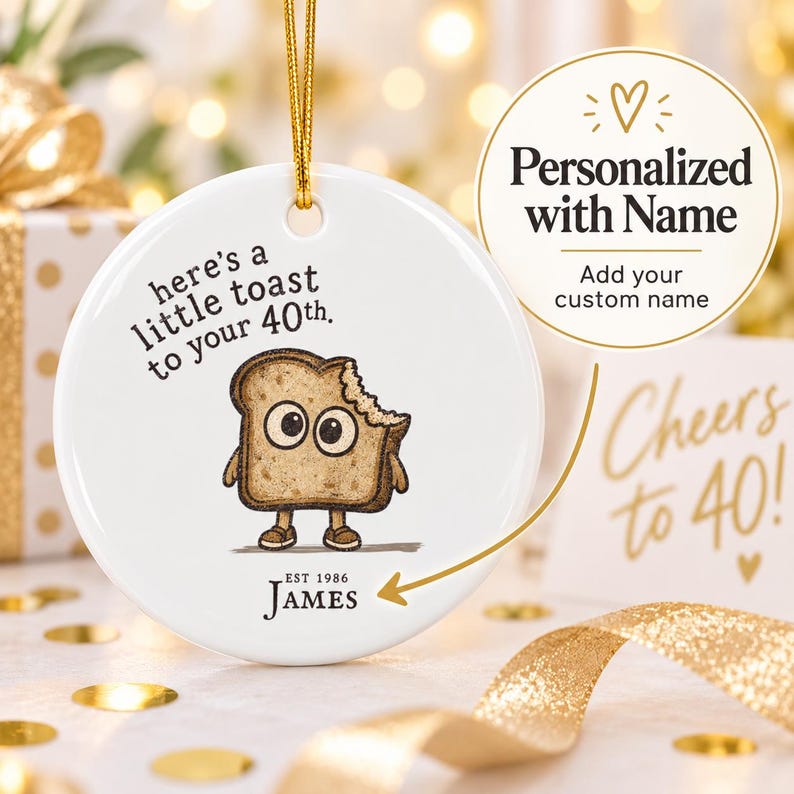 May include: A round white ceramic ornament hanging by a gold string. It features a cartoon slice of toast with eyes and legs, the text "here's a little toast to your 40th.", and the custom text "EST 1986 JAMES" printed in black ink.