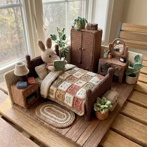 May include: A miniature bedroom set made of crocheted yarn, featuring a bed with a patchwork quilt, a nightstand with a lamp, a wardrobe, and a vanity with a mirror. A crocheted rabbit figure sits in the bed reading a small green book.