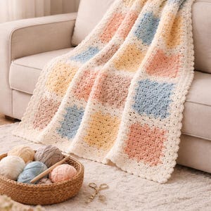 Peut inclure: Une couverture au crochet aux couleurs pastel, rose, jaune, bleu et crème, drapée sur un canapé beige. Un panier de pelotes de laine et des ciseaux suggèrent un thème artisanal. La couverture présente un motif carré.