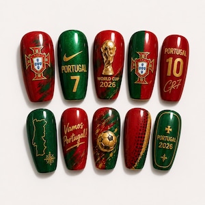 Puede incluir: Un juego de diez uñas postizas con diseños en rojo y verde con detalles dorados. Las uñas muestran el escudo nacional de Portugal, el texto 'PORTUGAL 7', 'WORLD CUP 2026', 'Vamos Portugal!', 'PORTUGAL 10 CR7', 'PORTUGAL 2026', además de un trofeo y un balón de fútbol en 3D.