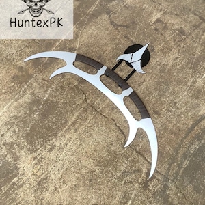 Könnte beinhalten: Eine silberne und braune Klingonische Bat'leth-Waffe. Die gebogene Klinge hat eine silberne Oberfläche mit einem braunen Griff. Die Waffe wird auf einem schwarzen Ständer mit einem weißen Emblem ausgestellt. Das Logo "HuntePK" befindet sich in der oberen linken Ecke.