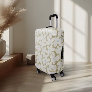 Peut inclure: Une valise à roulettes avec une housse à motifs floraux. La housse présente un motif de grandes fleurs blanches avec des centres bleu clair sur un fond vert clair. La valise a une poignée et des roues noires.