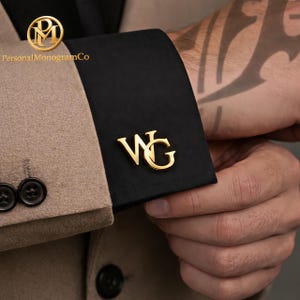 Può includere: Gemelli dorati con le iniziali "WG" su un polsino nero. La persona indossa un blazer beige. Il logo del marchio "Personal Monogram Co" è visibile nell'angolo in alto a sinistra. Un accessorio elegante.