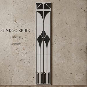May include: A vertical Art Deco design, the "Ginkgo Spire," features a black and white color scheme. The design includes geometric shapes and lines, with the word "PEWTER" and "Art Deco" displayed. The spire is mounted on a textured, light-colored wall.