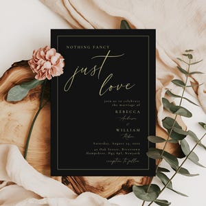 May include: A black wedding invitation with gold lettering. The text reads "Nothing Fancy, Just Love", with the names Rebecca Anderson and William Ribsen. The invitation is set against a backdrop of a pink flower and green foliage.