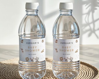 Op de afbeelding: Twee doorzichtige plastic waterflessen met witte doppen. Elke fles heeft een etiket met de tekst "Jordan's Baby Shower" met dierenillustraties. De datum 06.17.20XX staat ook op het etiket. De flessen staan op een geweven mat.