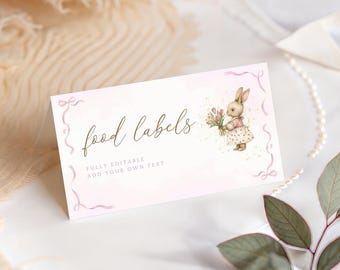Puede incluir: Una etiqueta de comida rosa claro con las palabras "food labels" en escritura elegante. La etiqueta presenta una ilustración de acuarela de un conejito sosteniendo flores. También se incluye el texto "FULLY EDITABLE ADD YOUR OWN TEXT". La etiqueta tiene un borde de cinta rosa.