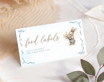 Puede incluir: Tarjeta blanca para etiquetas de alimentos con la inscripción "food labels" en escritura dorada. La tarjeta presenta una ilustración de acuarela de un conejito sosteniendo flores y detalles de cinta azul. El texto "FULLY EDITABLE ADD YOUR OWN TEXT" también está en la tarjeta.