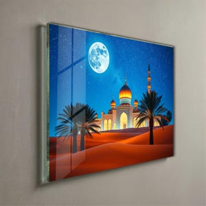 May include: A framed print depicting a desert scene at night. A large, full moon illuminates a mosque with multiple domes and a tall minaret. Palm trees and sand dunes are in the foreground, under a starry sky.