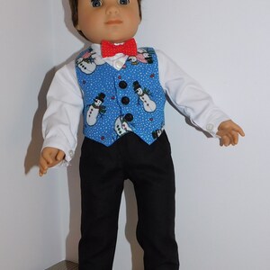 May include: A doll wearing a blue vest with a snowman pattern, a red bow tie, a white shirt, black pants, and black shoes.
