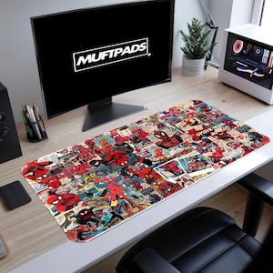 May include: A rectangular desk mouse pad featuring a collage of Spider-Man comic book panels in red, blue, and black. The pad is on a white desk, with a computer monitor displaying the text "MUFTPADS".