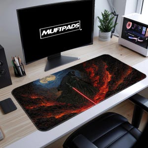 Könnte beinhalten: Rechteckige Schreibtischunterlage mit einer dramatischen Illustration von Darth Vader mit einem roten Lichtschwert, vor einer feurigen, vulkanischen Landschaft. Auf dem Bildschirm steht der Text "MUFTPADS".