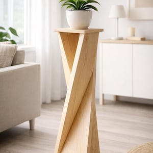 May include: A light-coloured wooden plant stand with a unique twisted design. The stand holds a white pot with a green plant. The stand is approximately 76 cm tall and has a square base.
