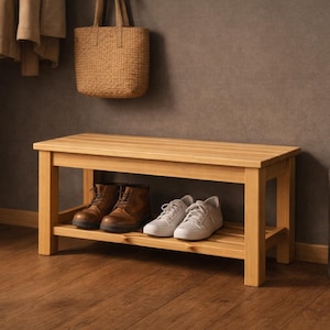 Peut inclure: Un banc en bois clair avec une étagère inférieure, contenant deux paires de chaussures. Un sac fourre-tout en cuir marron est suspendu au mur au-dessus du banc. Un parapluie est dans un porte-parapluie cylindrique gris foncé.