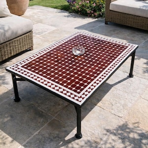 May include: Rectangular outdoor coffee table with a mosaic tile top. The tile pattern features a repeating design of red and white squares. The table has a black metal frame and legs. A small glass bowl sits on the table's surface.