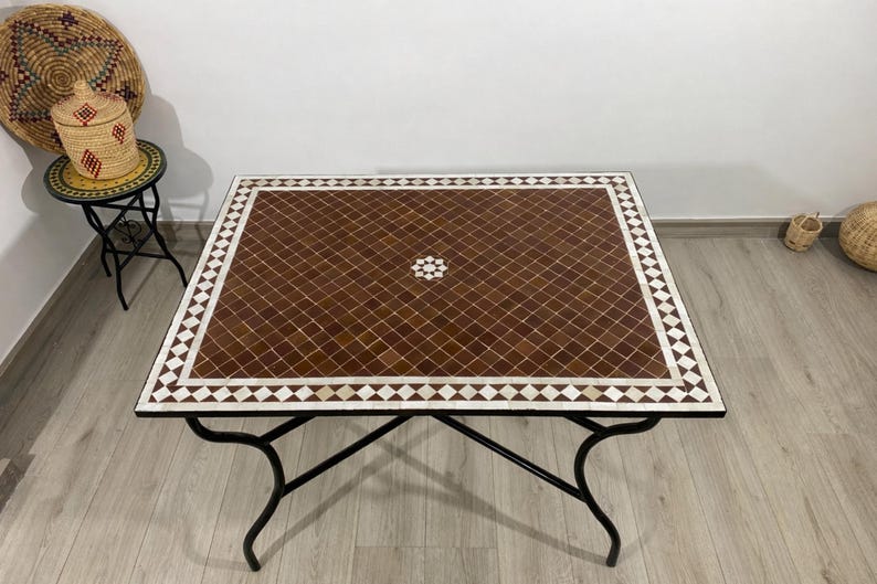 K&ouml;nnte beinhalten: Quadratischer Mosaiktisch mit braunem und wei&szlig;em geometrischen Muster. Der Tisch hat ein schwarzes Metallgestell mit geschwungenen Beinen. Die Tischplatte besteht aus kleinen, quadratischen Fliesen in Braun- und Wei&szlig;t&ouml;nen, die in einem Rautenmuster angeordnet sind.