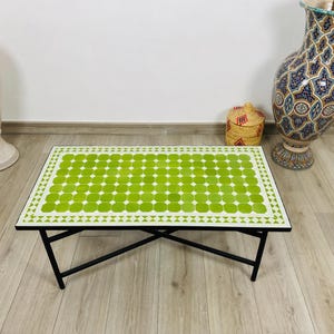 Könnte beinhalten: Rechteckiger Couchtisch mit grün-weißer Fliesenplatte und schwarzen Metallbeinen. Die Tischplatte hat ein Muster aus grünen Kreisen. Der Tisch ist ein dekoratives Stück für ein Wohnzimmer.