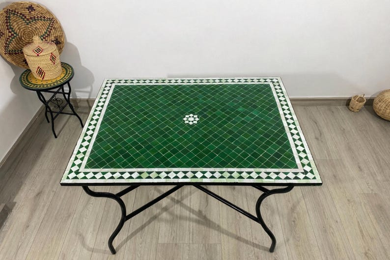 K&ouml;nnte beinhalten: Quadratischer Couchtisch mit gr&uuml;ner Mosaikfliesenplatte und schwarzem Metallgestell. Das Mosaik ist ein Gittermuster aus kleinen gr&uuml;nen Fliesen mit wei&szlig;em Rand. Der Tisch ist ca. 100 cm lang und breit.
