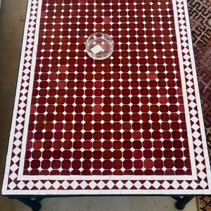 May include: A white ceramic mug with a black handle and the text "But First, Coffee" in a bold, black font. The mug is set against a blurred background, suggesting a cosy setting.