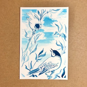 May include: A rectangular art print featuring a blue ink illustration of two birds perched on thin branches. The birds are rendered in varying shades of blue against a white background, with one bird looking down and the other looking up.