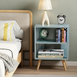 Narrow nightstand styled next to bed with lamp and clock
