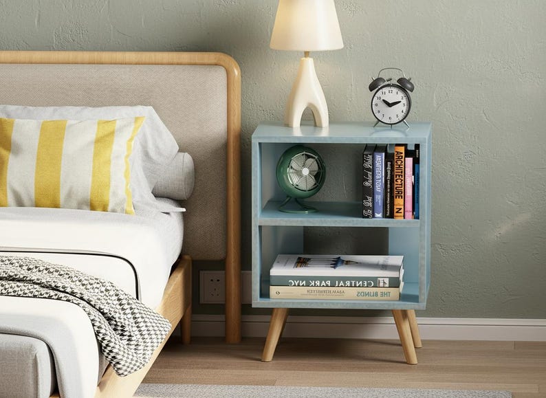 Narrow nightstand styled next to bed with lamp and clock