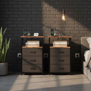 May include: Two matching nightstands with three drawers each, a wooden top, and a black metal frame. Each nightstand has a lamp, a phone, and a small digital clock on top. A tall potted plant is to the left.