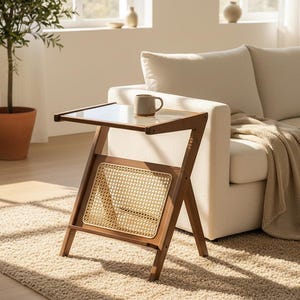 May include: A wooden side table with a clear glass top and a woven rattan shelf. The table has a Z-shaped frame and is positioned next to a white sofa. A mug sits on the table. The table is approximately 24 inches tall.