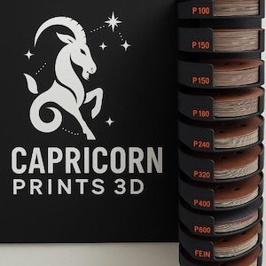 May include: A black display stand holding brown sanding discs, labelled with grit sizes from P100 to FEIN. Beside it is a black panel with a white Capricorn logo and the text "CAPRICORN PRINTS 3D."