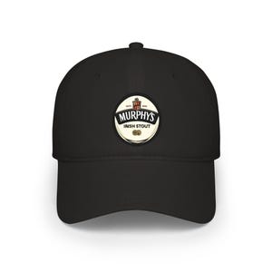 Puede incluir: Gorra de béisbol negra con un parche circular que muestra "Murphy's Irish Stout" en blanco y rojo. El parche incluye la fecha de establecimiento de 1856. La gorra tiene una visera curva y una corona estructurada.