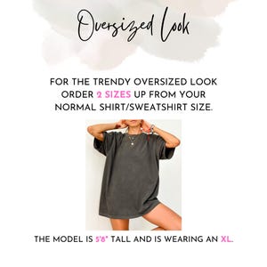 May include: A charcoal grey short-sleeved t-shirt with a loose fit. Text reads: Oversized Look, FOR THE TRENDY OVERSIZED LOOK ORDER 2 SIZES UP FROM YOUR NORMAL SHIRT/SWEATSHIRT SIZE, THE MODEL IS 5'8" TALL AND IS WEARING AN XL.
