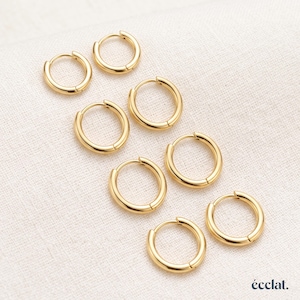 May include: A set of six gold-toned hoop earrings arranged in a staggered pattern. Each earring features a smooth, circular metal band with a simple hinge closure mechanism. The jewellery pieces are polished and have a consistent metallic yellow finish.