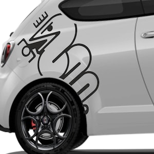 Könnte beinhalten: Ein weißes Auto mit einem schwarzen Grafikdesign an der Seite. Das Design scheint ein stilisiertes Logo oder Emblem zu sein. Das Auto hat schwarze Räder mit einem roten Bremssattel.
